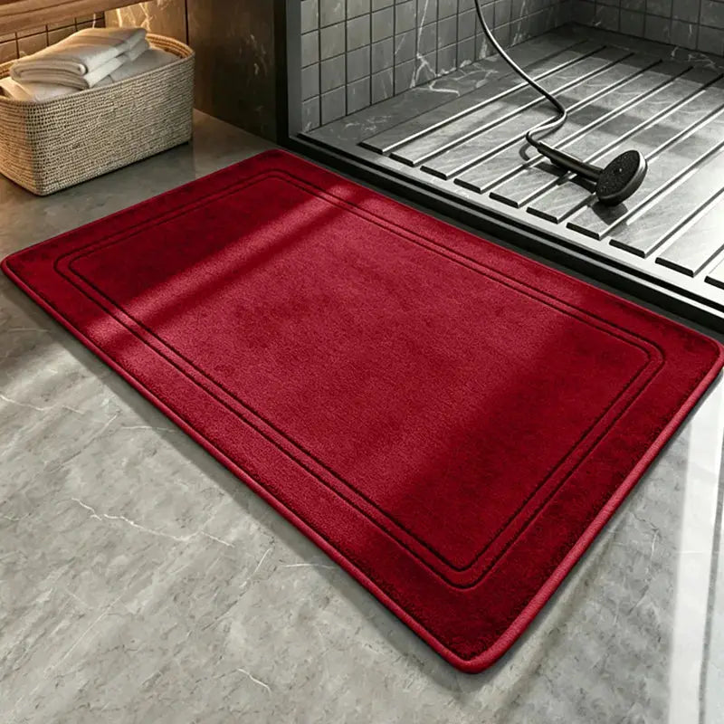 Red plush bathroom rug placed by the shower, with bordered design and soft texture.