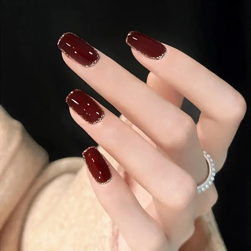 Gel nail polish set manicure: five burgundy nails with gold glitter tips