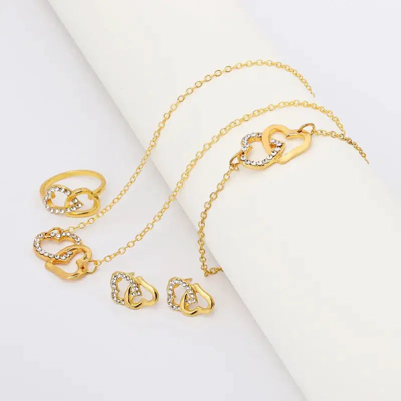 Simples Market five-piece gold-tone heart jewelry set: rhinestone pendant necklace, two heart rings, and heart stud earrings.