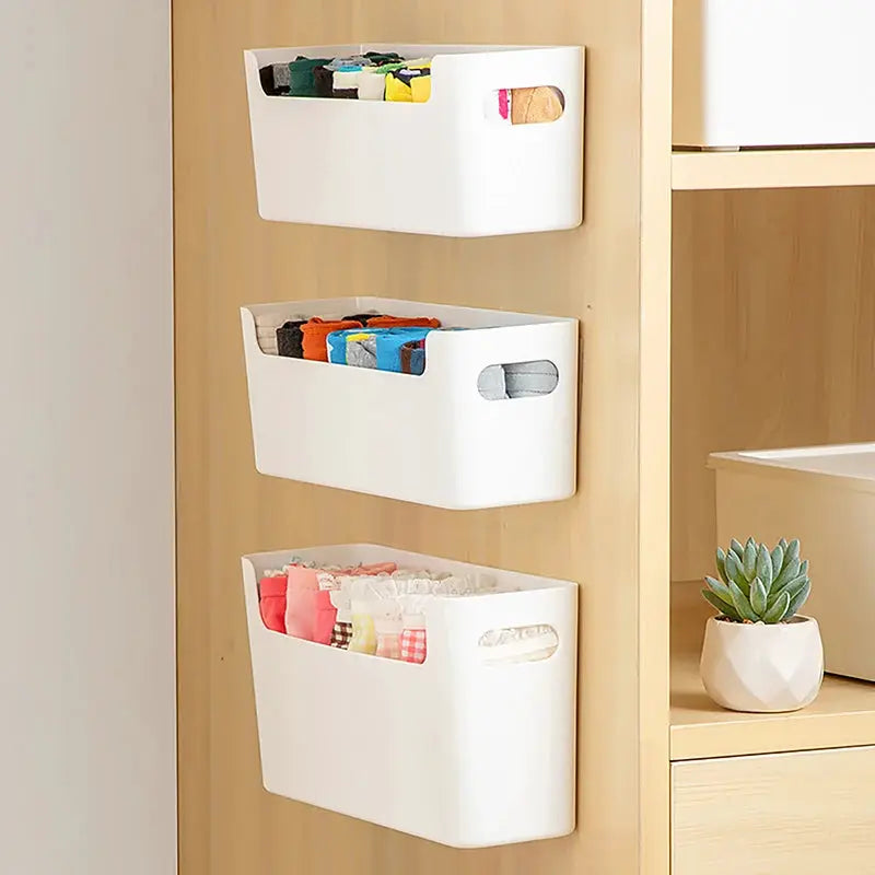 White plastic cabinet door organiser with three wall-mounted bins for cling film and kitchen wraps.