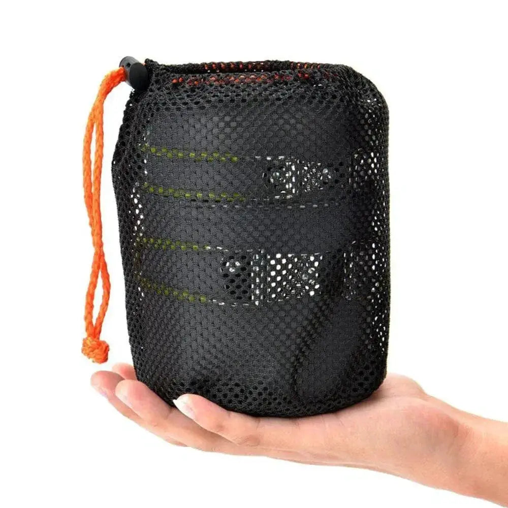Camping cookware mess kit in ultralight pots, carried in a black mesh pouch with an orange drawstring