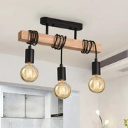 Retro wooden beam chandelier with three hanging bulbs, black sockets and spiraled cords.