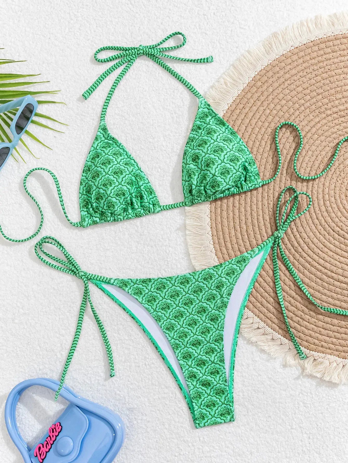 Women's green printed triangle bikini set with adjustable tie-side straps on a bright sandy beach scene