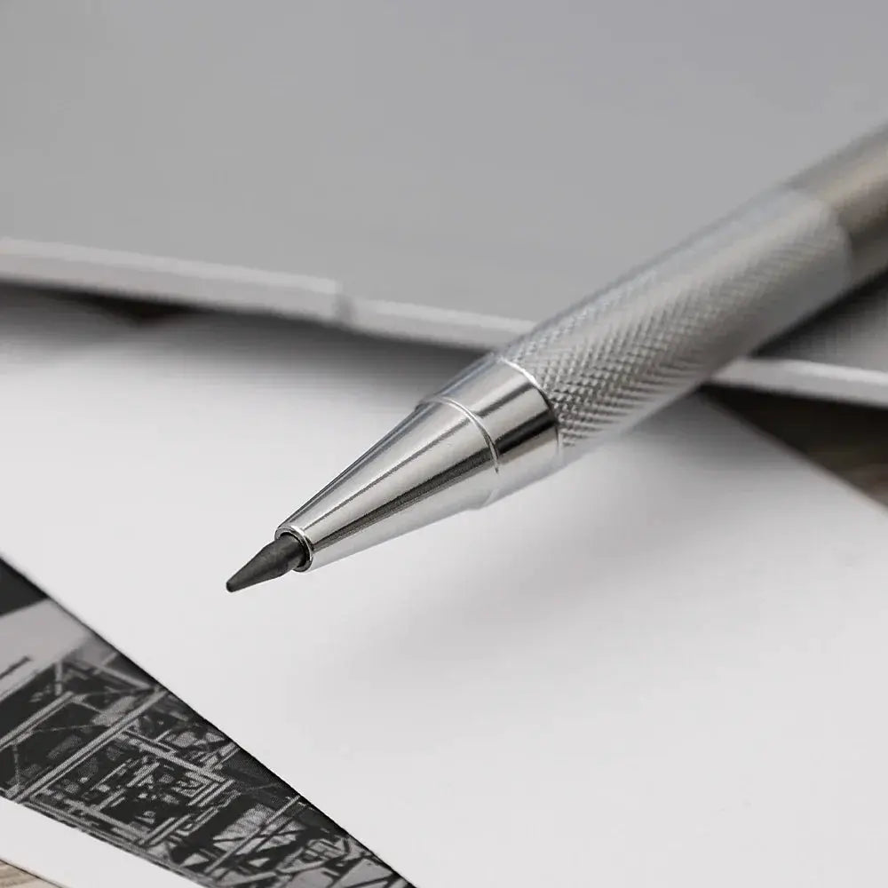 Metal mechanical pencil with knurled silver grip and pointed tip on white paper.