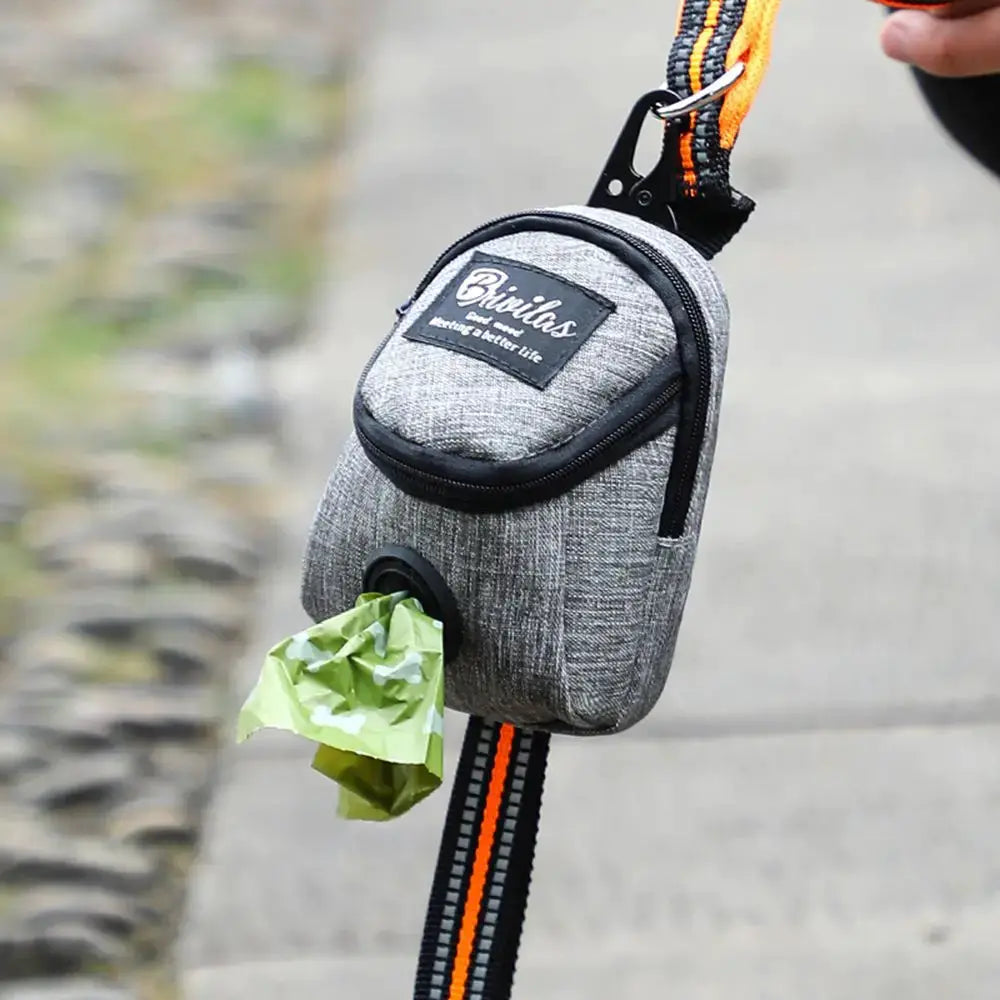 Pet dog treat pouch by Simples Market, gray fabric training bag with orange-black strap and poop bag dispenser.