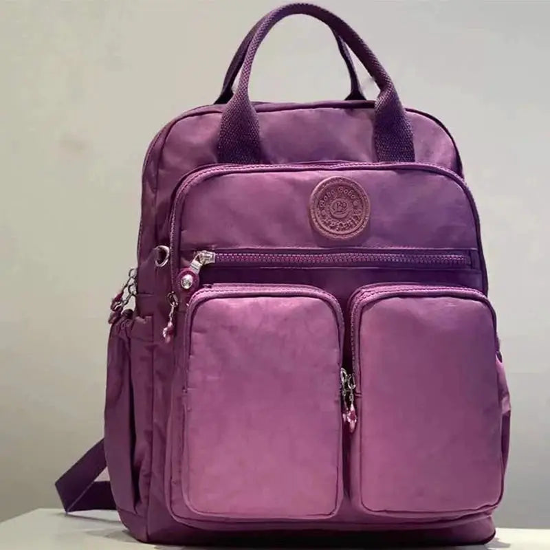 Simples Market purple nylon backpack with multiple zip pockets and top handle.
