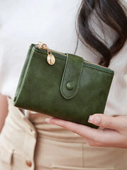 Minimalist women's wallet with double gold zippers and snap strap in green leather