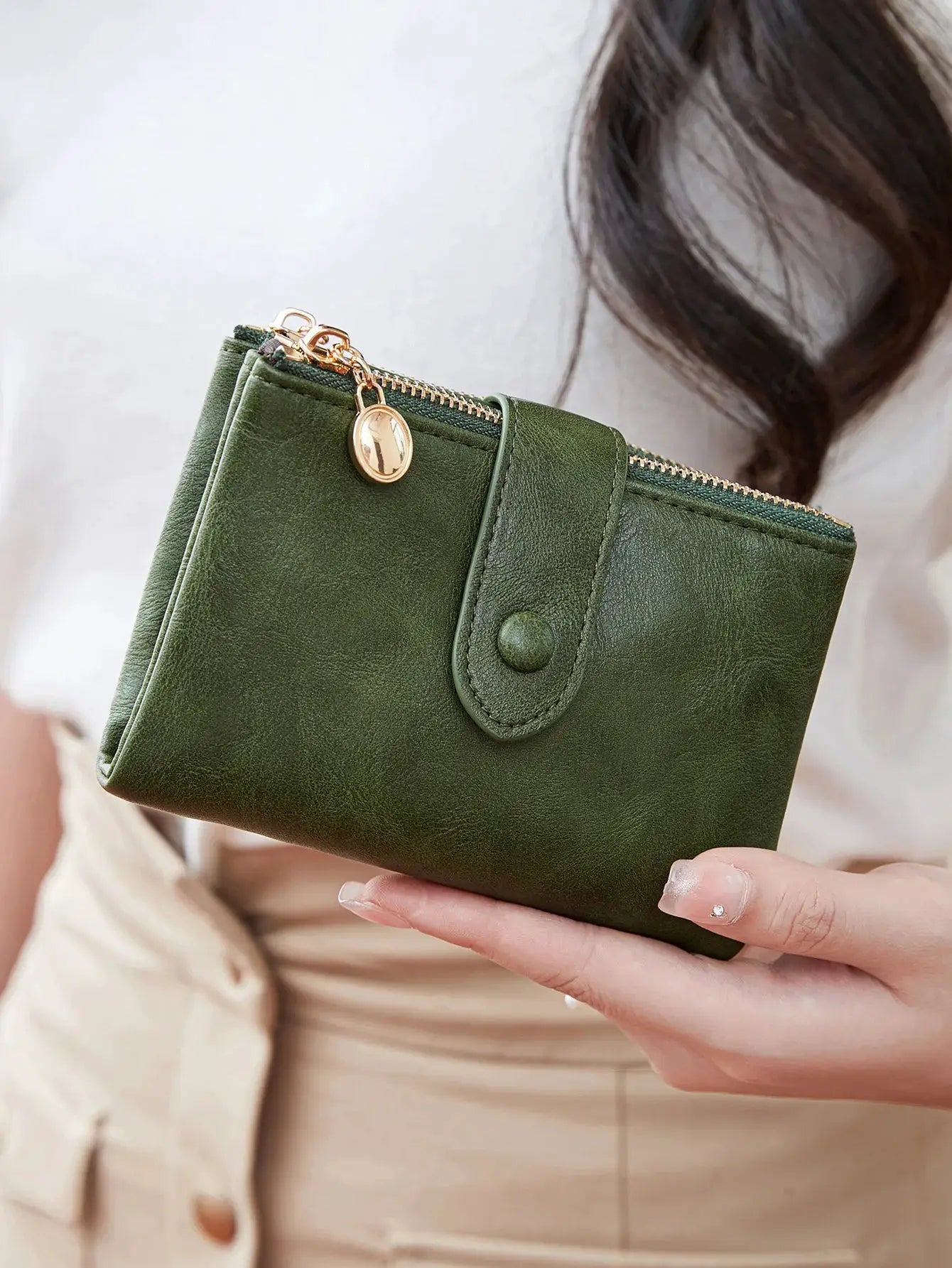Minimalist women's wallet with double gold zippers and snap strap in green leather