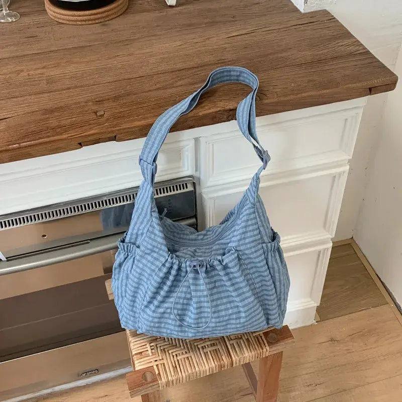 Nylon shoulder bag in blue plaid with drawstring closure and single strap