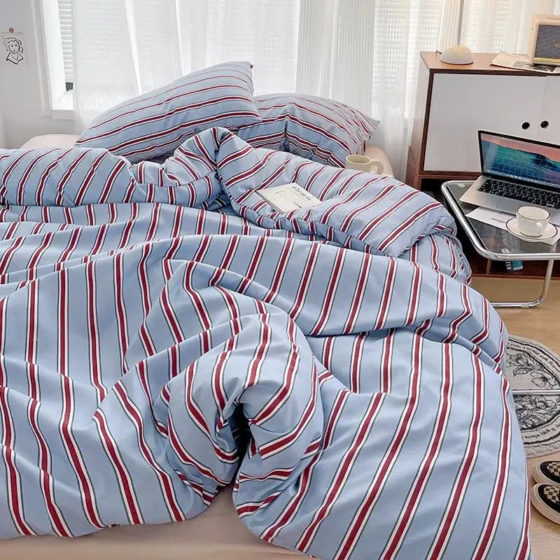 Duvet cover and four-piece washed cotton sheet set in red and blue stripes on a bed