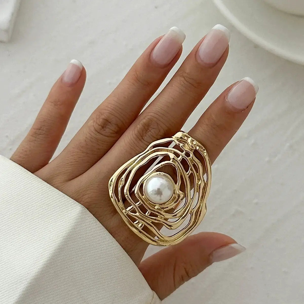 Ring: gold-toned metal with irregular three-layer frame and pearl centerpiece, adjustable