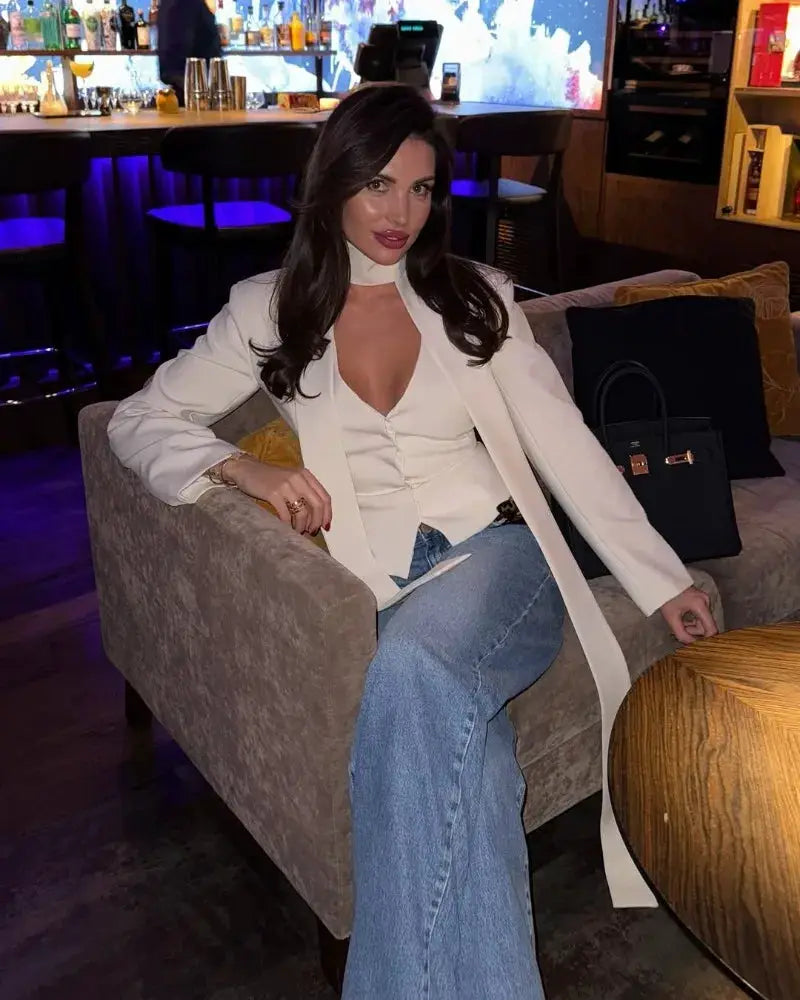 White blazer 2-piece set worn by a woman in a bar, featuring a V-neck top and light-wash jeans.