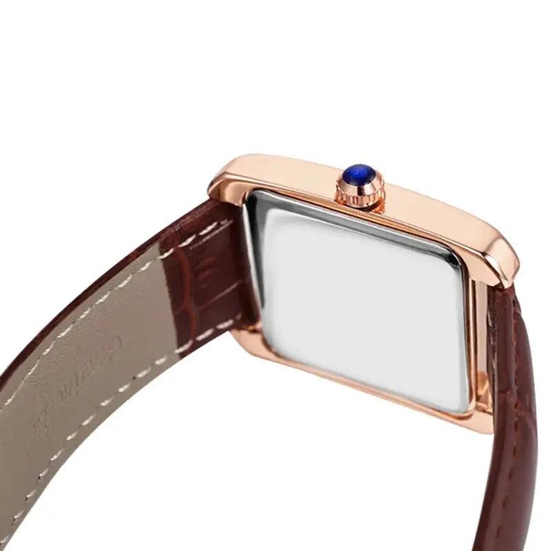 Wristwatch with rose-gold rectangular case, brown leather strap, and blue crown gem