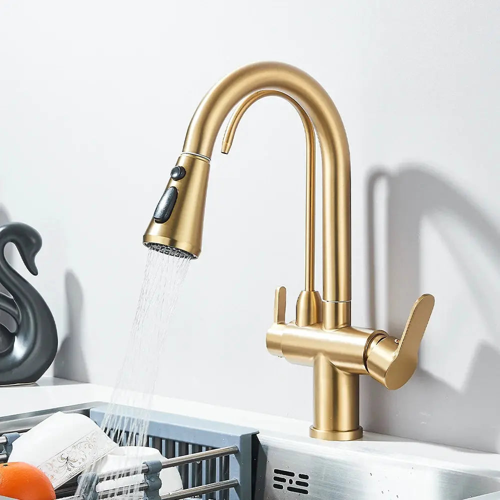 Gold brass pull-out kitchen faucet with dual handles, deck-mounted gooseneck over sink.