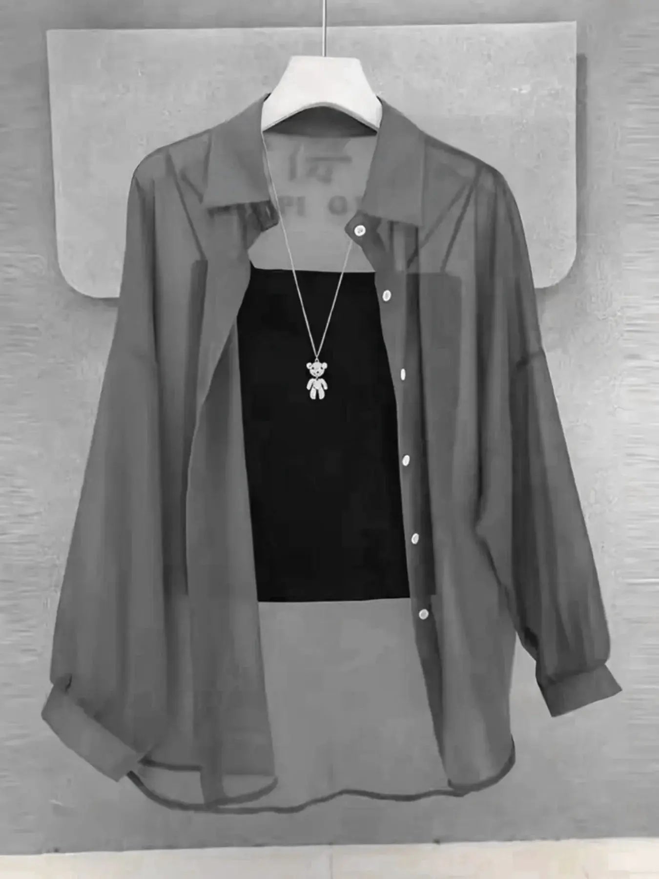 Plus-size ice-silk sheer chiffon blouse with long sleeves and button-down front, displayed on a hanger over a black top