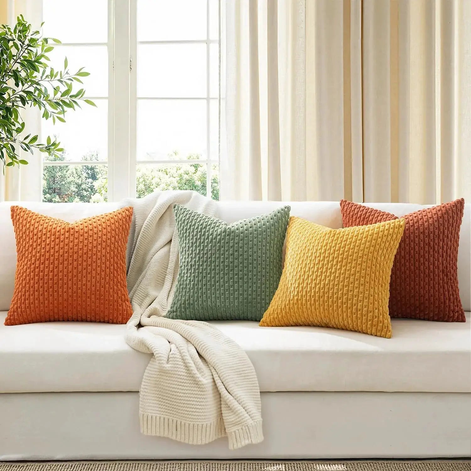 Throw pillow covers set, 20x20 in, corduroy texture in orange, green and yellow (4-pack) on a white sofa.
