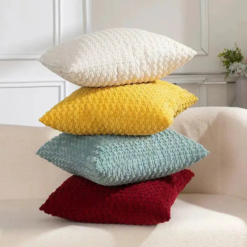 Soft velvet sofa cushions, set of 4 in white, yellow, teal, and red, stacked on a light sofa