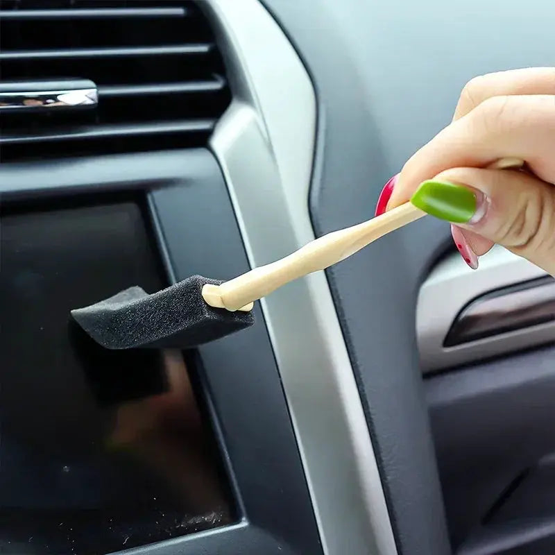 Car air vent cleaner brush with black foam tip on beige wooden handle for auto interior dust removal