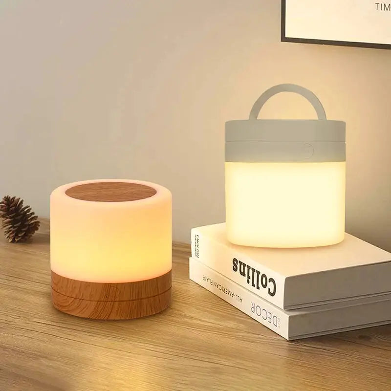 Two RGB color-changing night lamps; one wood-base with warm glow, the other white cylindrical lamp with handle.