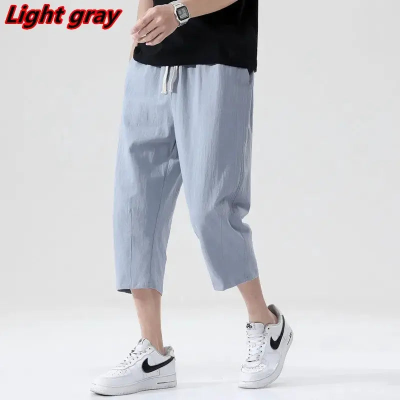 Men's light gray lightweight linen shorts with drawstring waist, cropped length, paired with Nike sneakers.