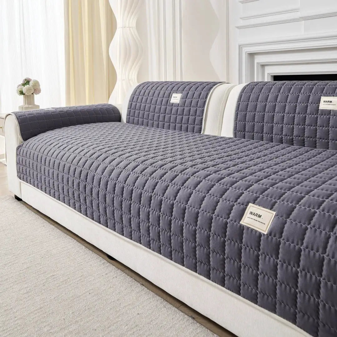 Plain Simple Solid Quilted Anti-Slip Sofa Cover by Simples Market in dark gray on a beige sofa