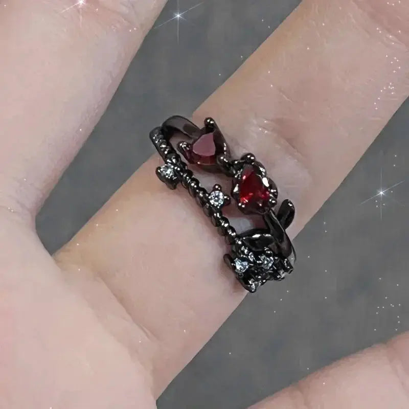 Goth punk open ring set on finger; black metal bands with red crystal heart and clear stones