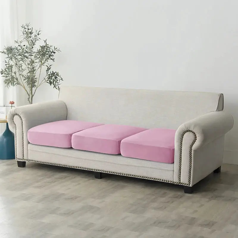 Plush elastic sofa slipcover in light gray with pink seat cushions on a three-seat couch