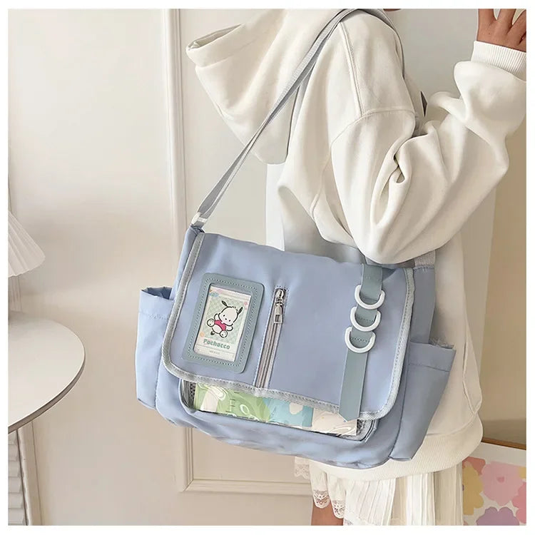 Light blue itabag crossbody with clear badge display window, side pockets, adjustable strap