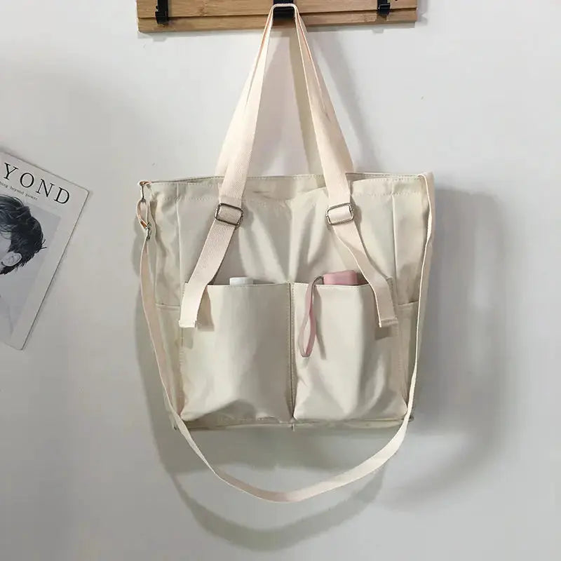 Women's waterproof Oxford tote bag in cream, large capacity with two front pockets and adjustable straps.