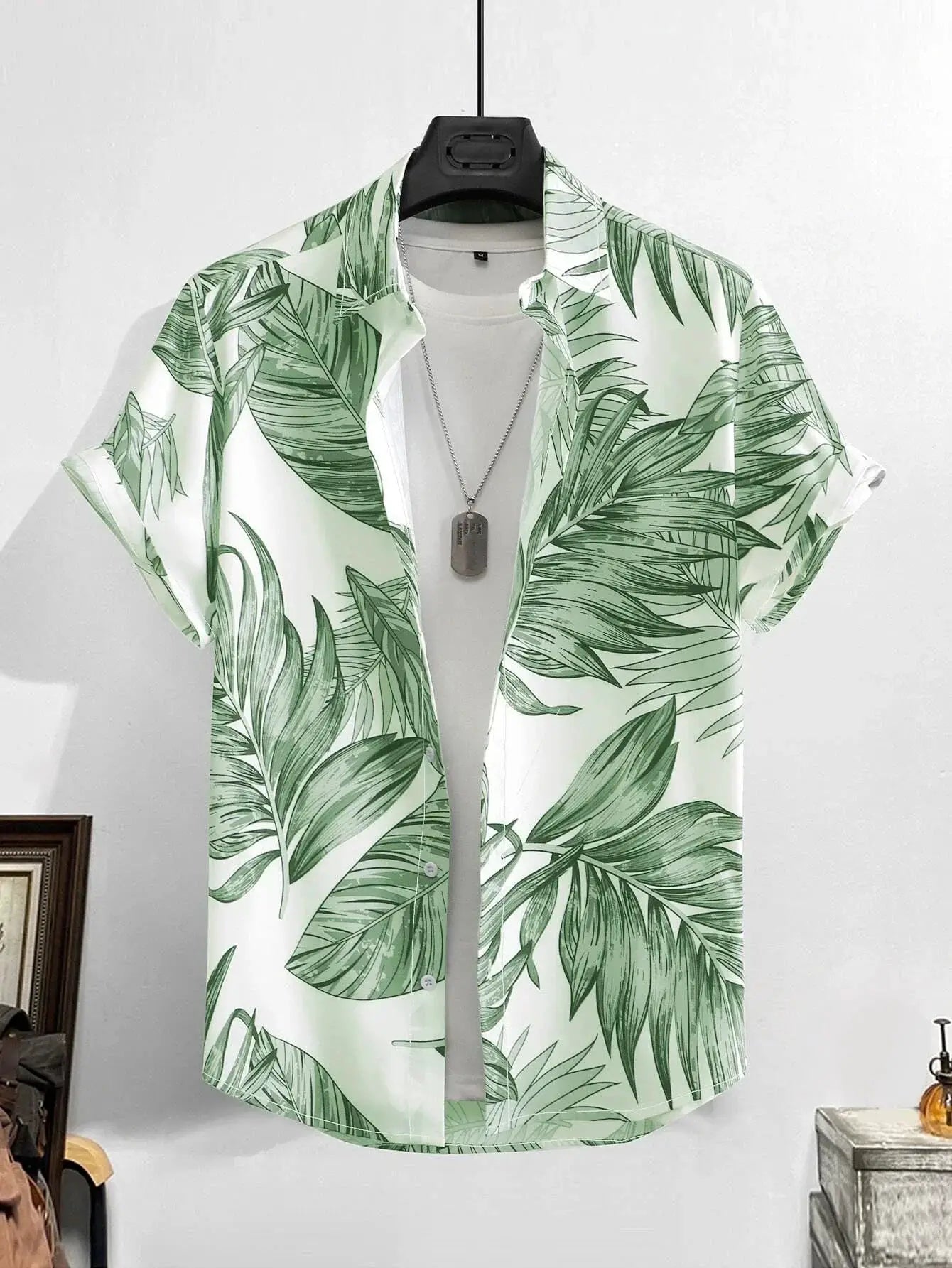 Hawaiian shirt with green palm-leaf print on white, layered over a white tee, on a hanger