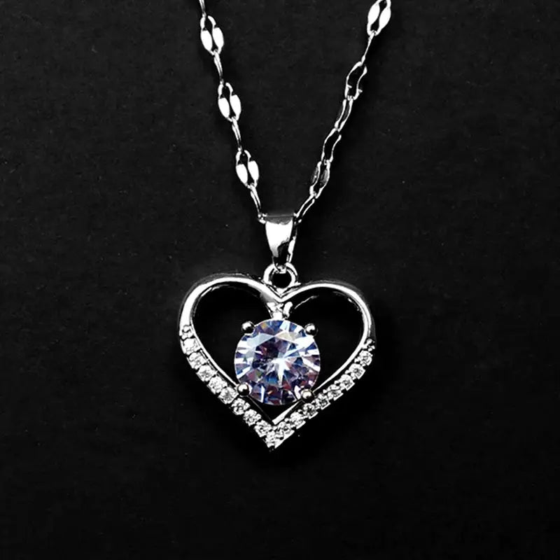 Heart pendant necklace with a silver-toned open-heart frame, pave crystals, and a central blue gemstone.