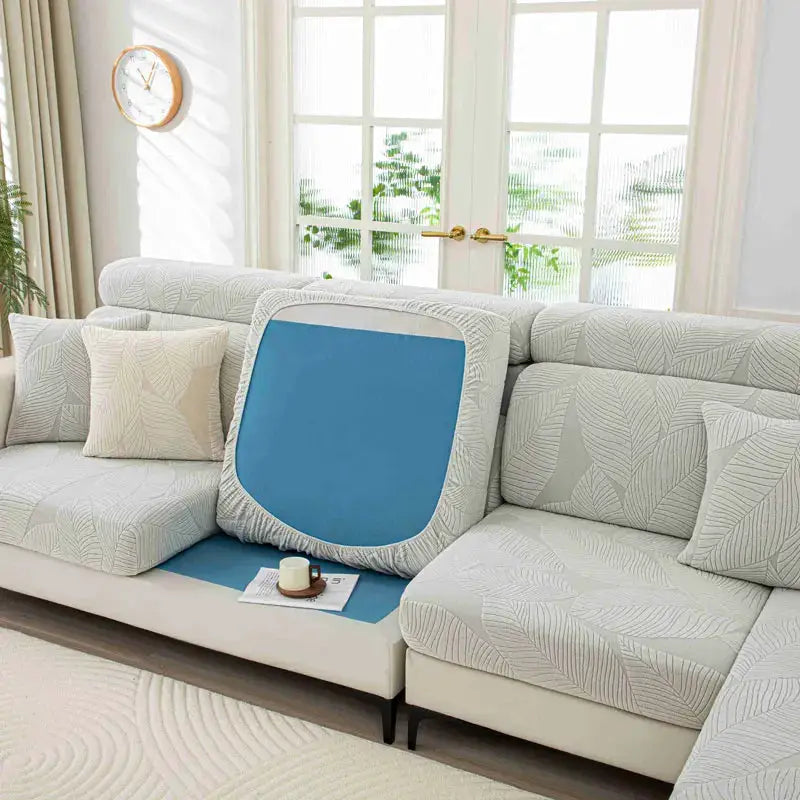 Sofa cushion cover, elastic thick plush in light gray leaf-pattern fabric with blue insert on sectional sofa