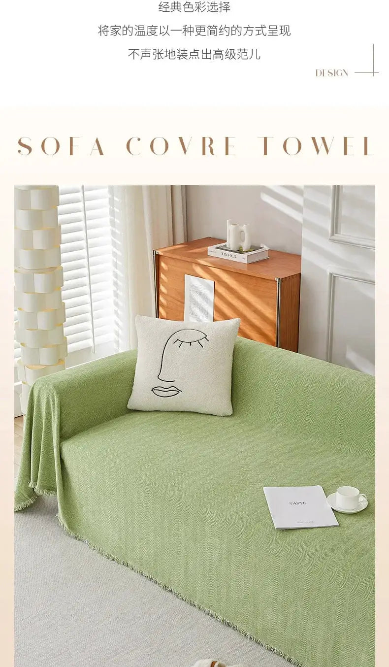 Couch cover in soft green chenille with fringe and herringbone texture on a sofa, accented by a white decorative pillow.