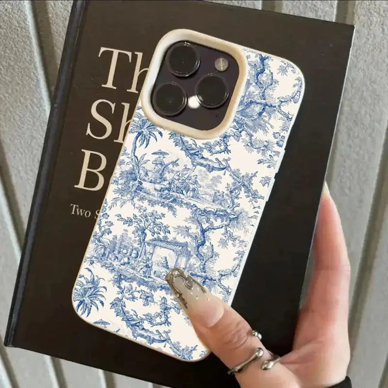 iPhone case with blue-and-white toile pattern, shockproof soft cover with a beige camera ring.