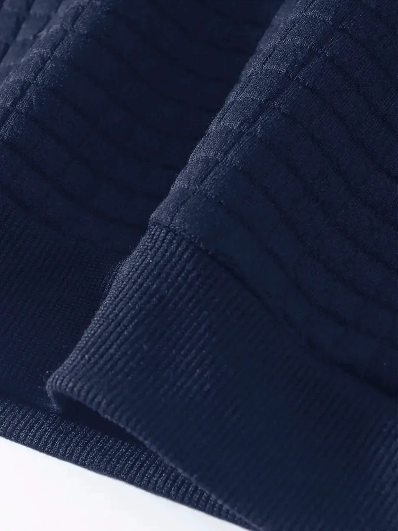 Men's navy knit crew-neck pullover sweater with ribbed cuffs; close-up fabric texture.