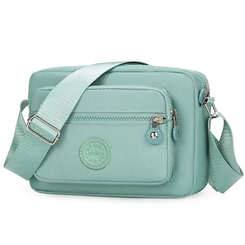 Crossbody bag by Simples Market in teal with front zipper pocket and adjustable strap