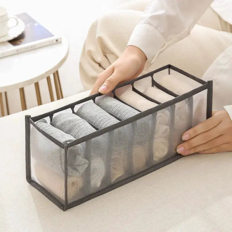 Clothes organizer box with gray mesh sides and six compartments for rolled socks.
