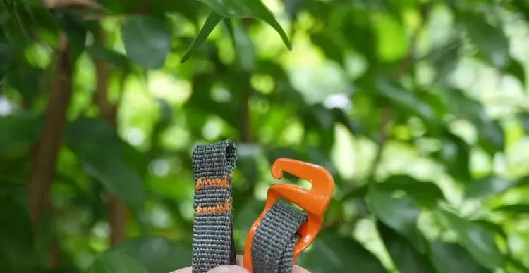 Camping luggage strap with orange quick-release buckle on gray nylon webbing