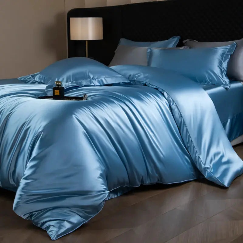 Silk satin bedding set in blue with duvet cover, fitted and flat sheets, and pillowcases on a bed