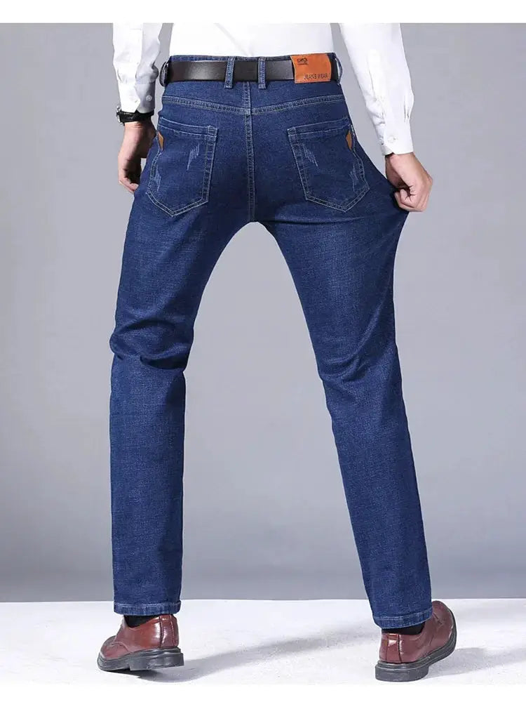 Men's blue denim jeans, straight fit with back pockets and stretch fabric, shown with belt and dress shoes.