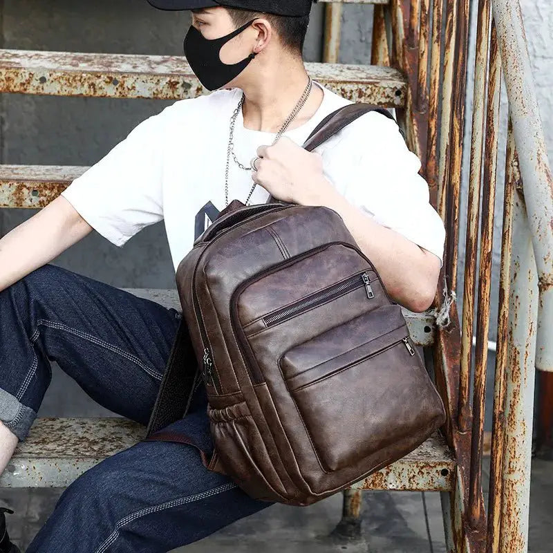 Person sitting on stairs with Professional USB Charging PU Leather Backpack, showcasing its stylish design and functionality.