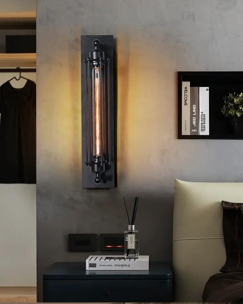 Industrial black iron wall light with vertical LED tube in metal frame for hallway or bedroom decor.
