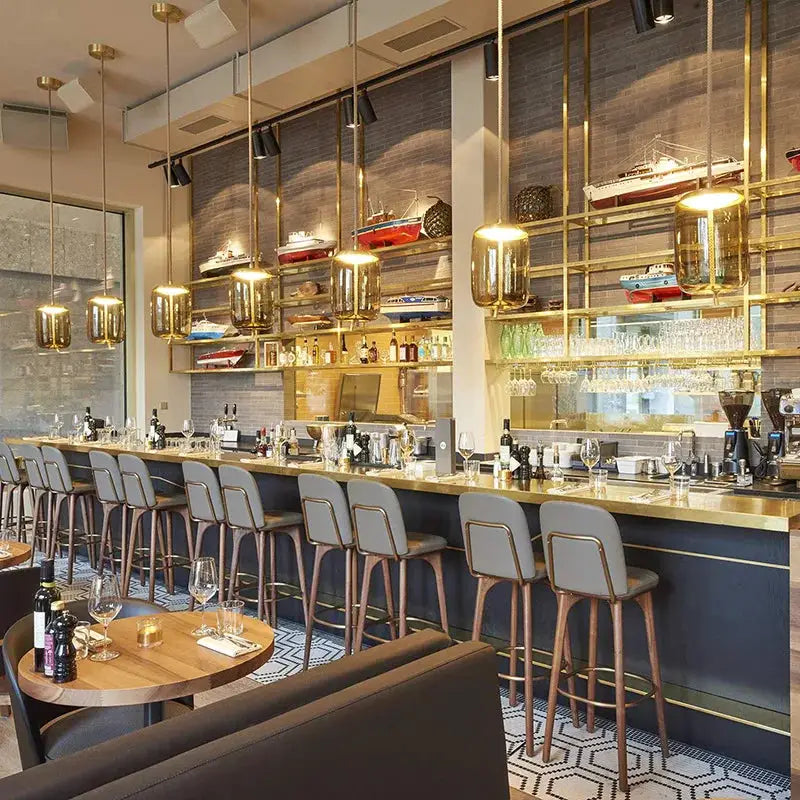 Pendant lamps with gold glass shades over a modern cafe bar; warm LED lighting