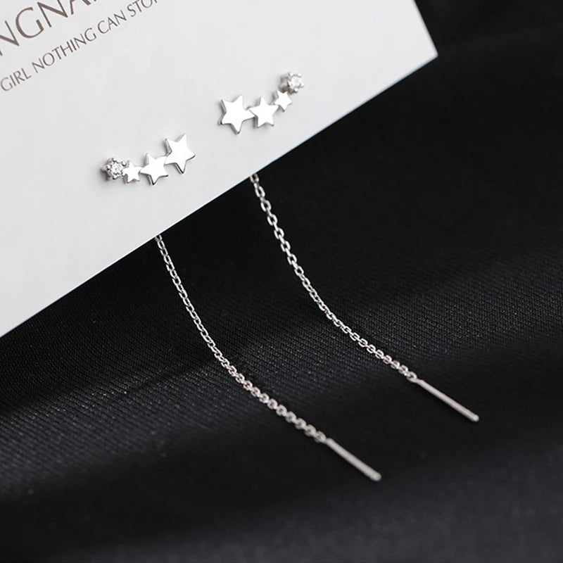 Pair of drop earrings with long silver thread-chain tassels and star bead accents by Simples Market