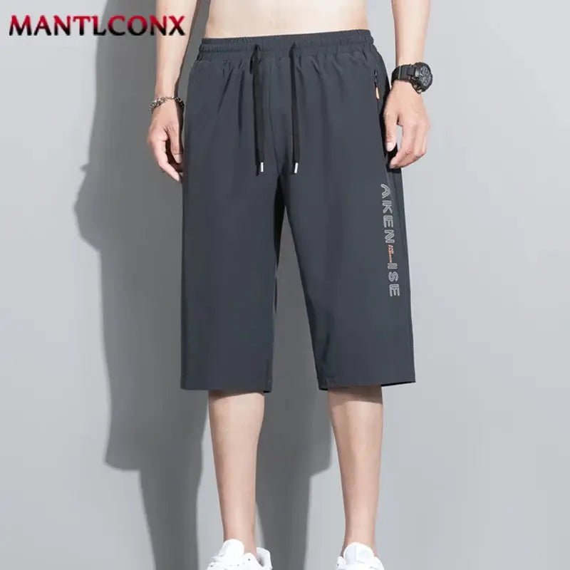 Men's black athletic shorts with elastic drawstring waist, knee-length, breathable quick-dry fabric; MANTLCONX logo.