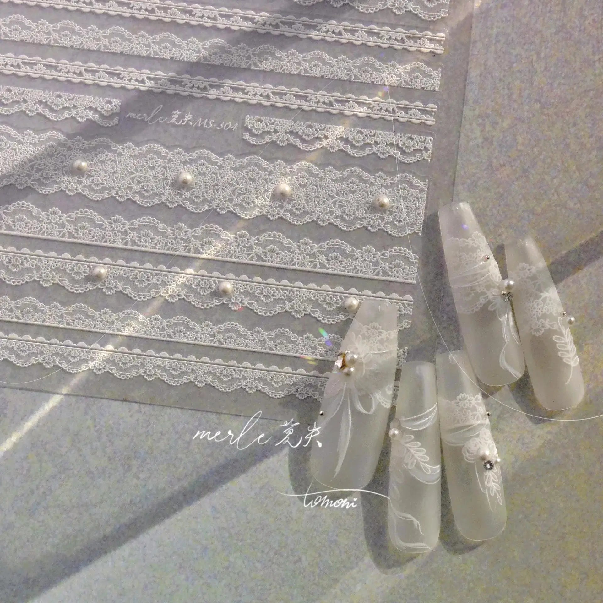 Nail art lace strips in white with floral lattice pattern and pearl accents on clear packaging
