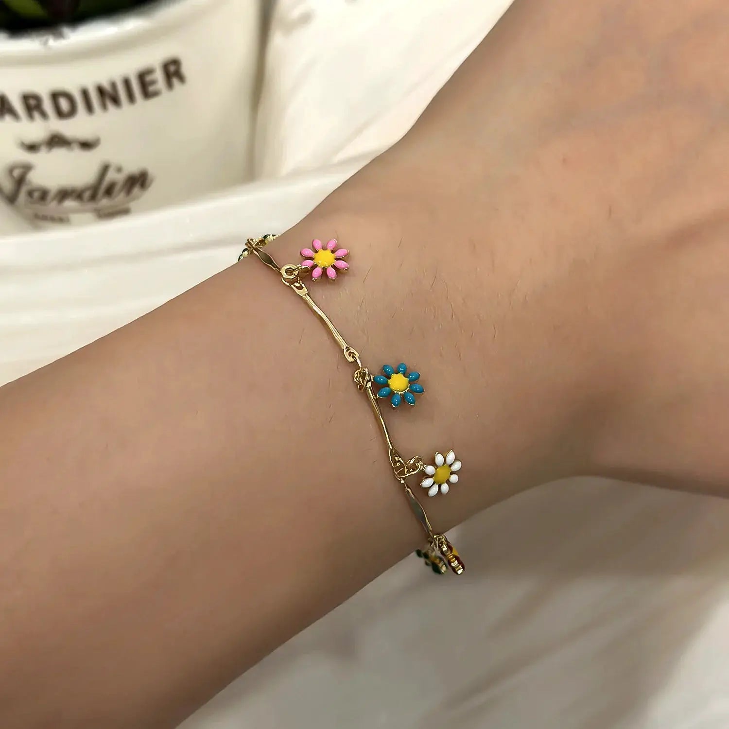Sweet Daisy Flower Bracelet for Women in gold tone with three daisy charms in pink, blue and white on wrist