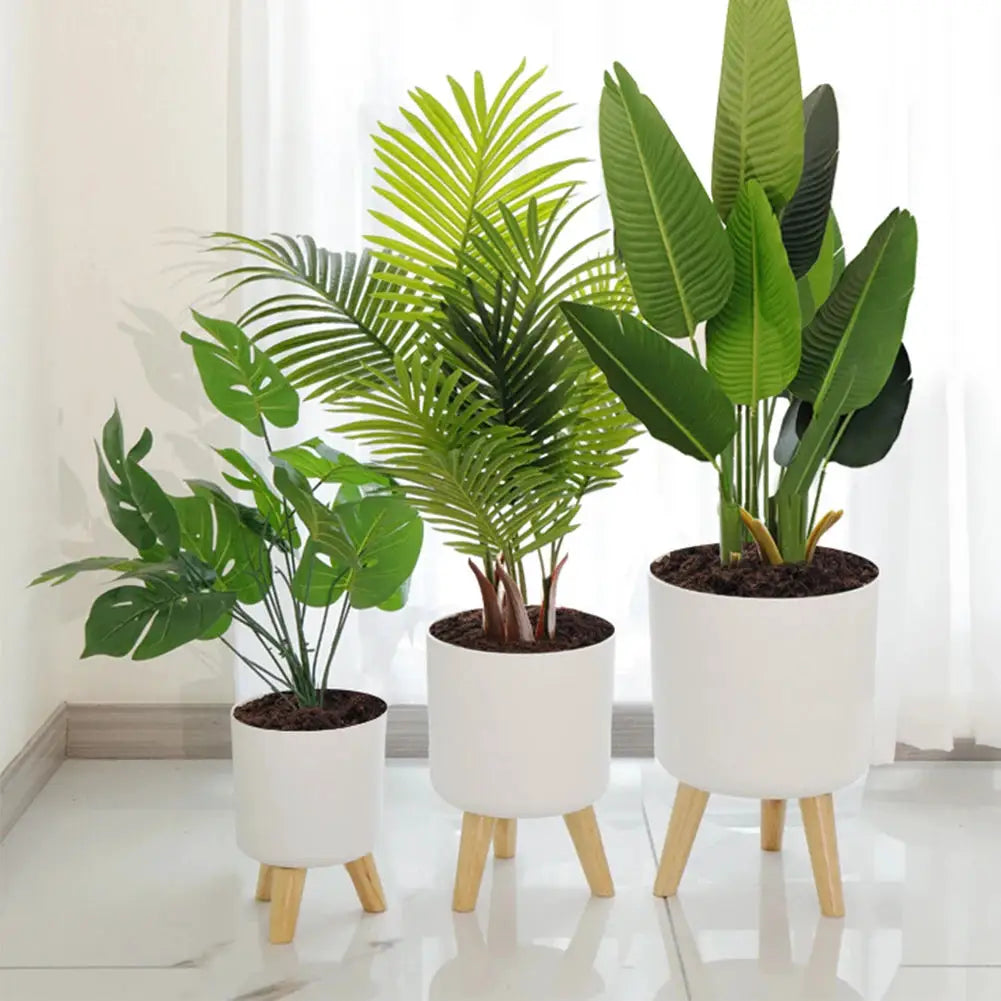 Three white floor-standing plant pots with wooden legs in varying sizes for indoor plants
