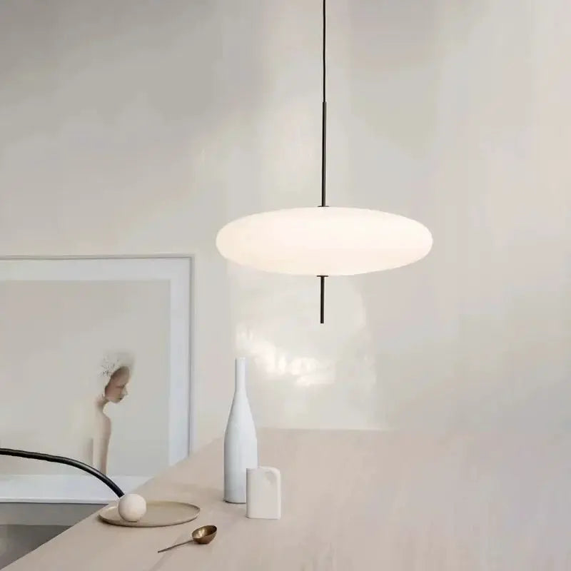 Nordic LED pendant light flying saucer design in white, suspended over a light wood table