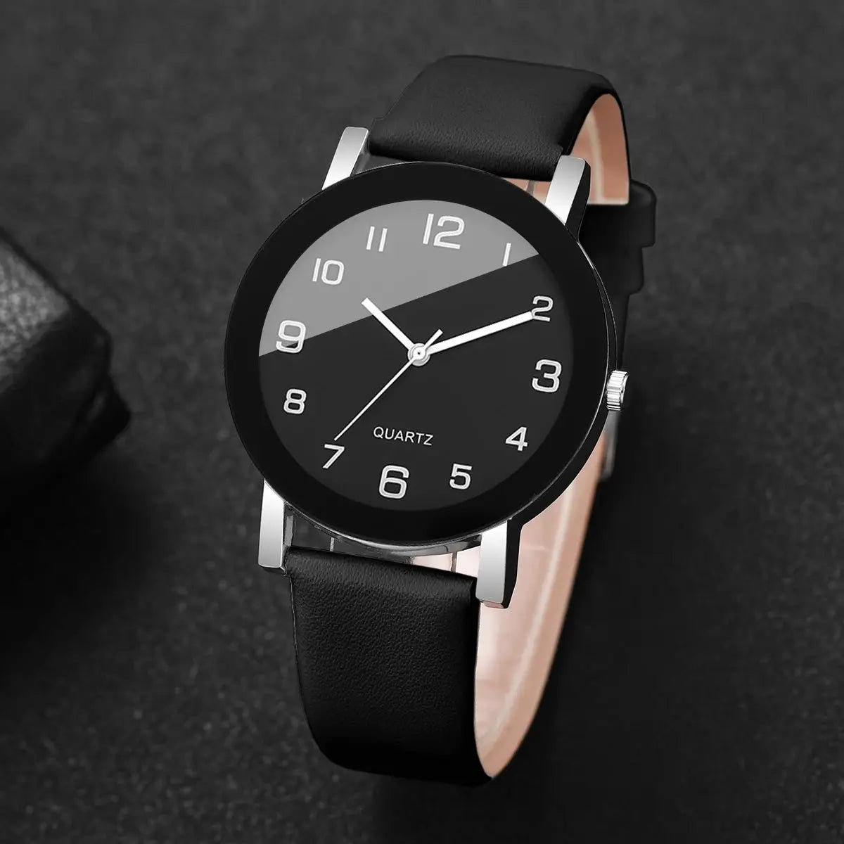 Unisex quartz wristwatch with black leather strap, silver case, two-tone dial and Arabic numerals.